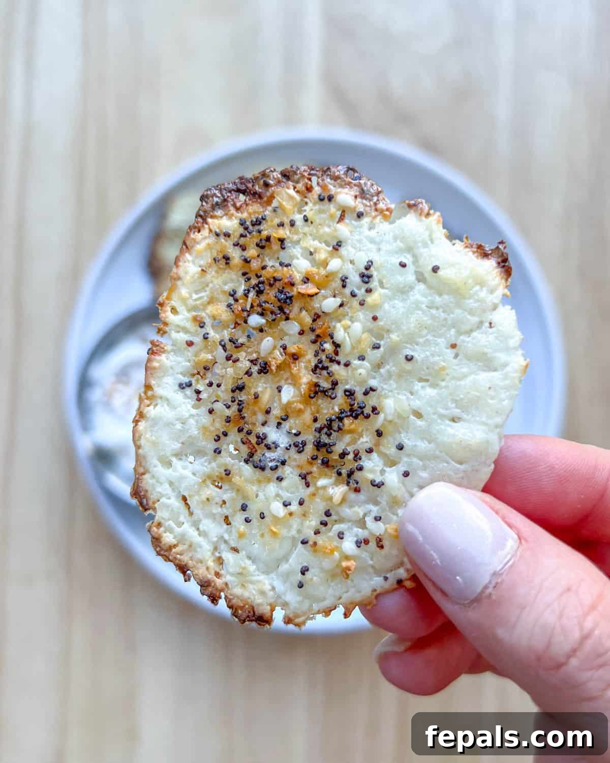 Crispy Cottage Cheese Bites 6 A hand delicately holding a single, perfectly baked cottage cheese chip, showcasing its crisp texture.