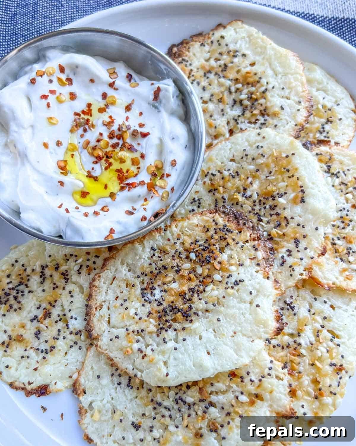 Crispy Cottage Cheese Bites 8 A charming plate with cottage cheese chips and a small side bowl of creamy white dipping sauce, ready for a delicious snack.