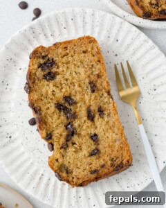 Power Banana Loaf 17 A perfectly baked slice of protein banana bread, showing its moist interior and chocolate chips, elegantly placed on a white plate ready to be enjoyed.
