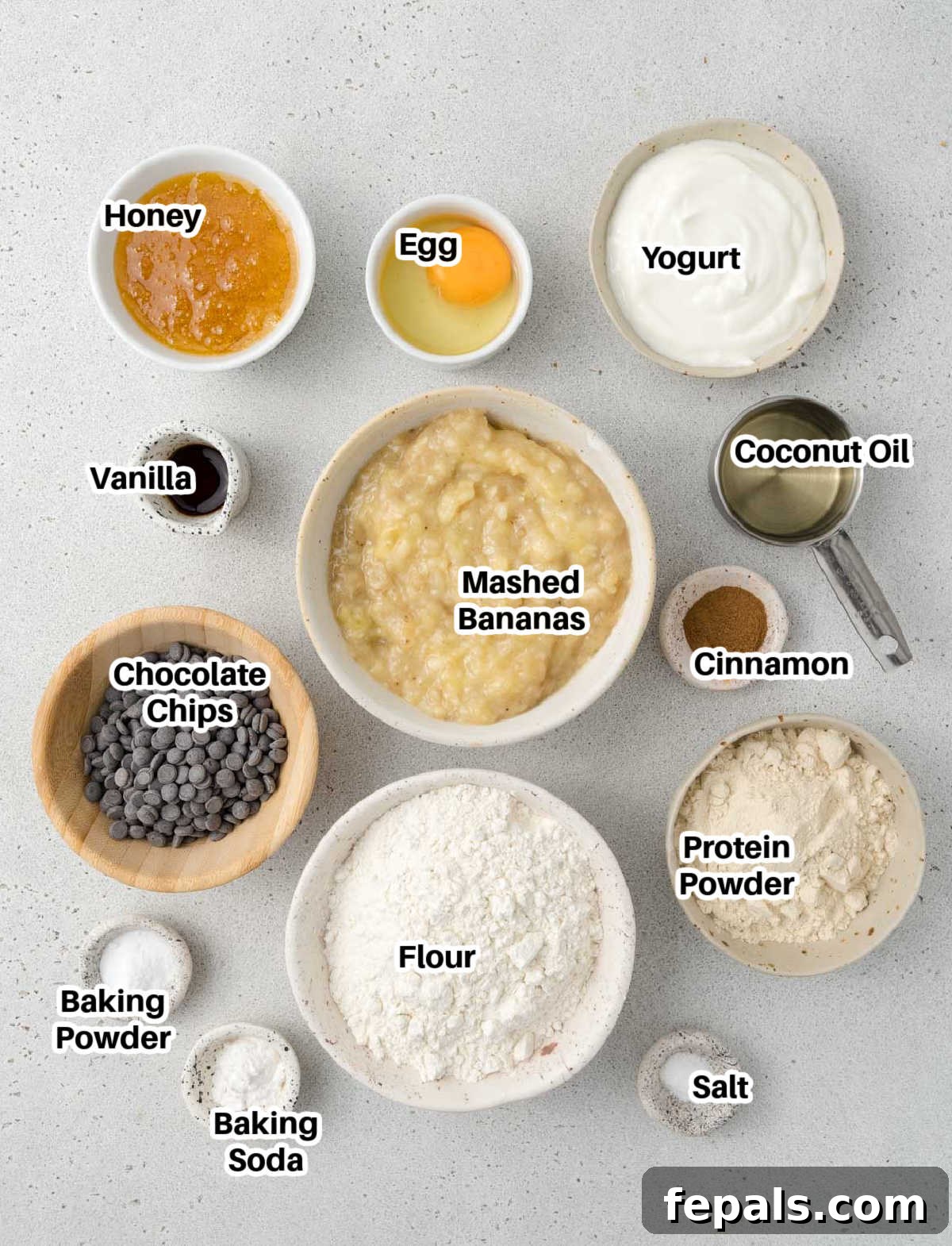 Power Banana Loaf 4 A beautifully arranged flat lay of all the fresh and pantry staple ingredients required to make delicious protein banana bread, including perfectly ripe bananas, eggs, creamy Greek yogurt, golden honey, and rich dark chocolate chips.