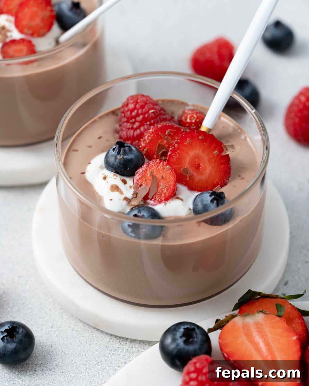Close-up of mousse with fresh berries and whipped cottage cheese, with a few strawberries on the side.