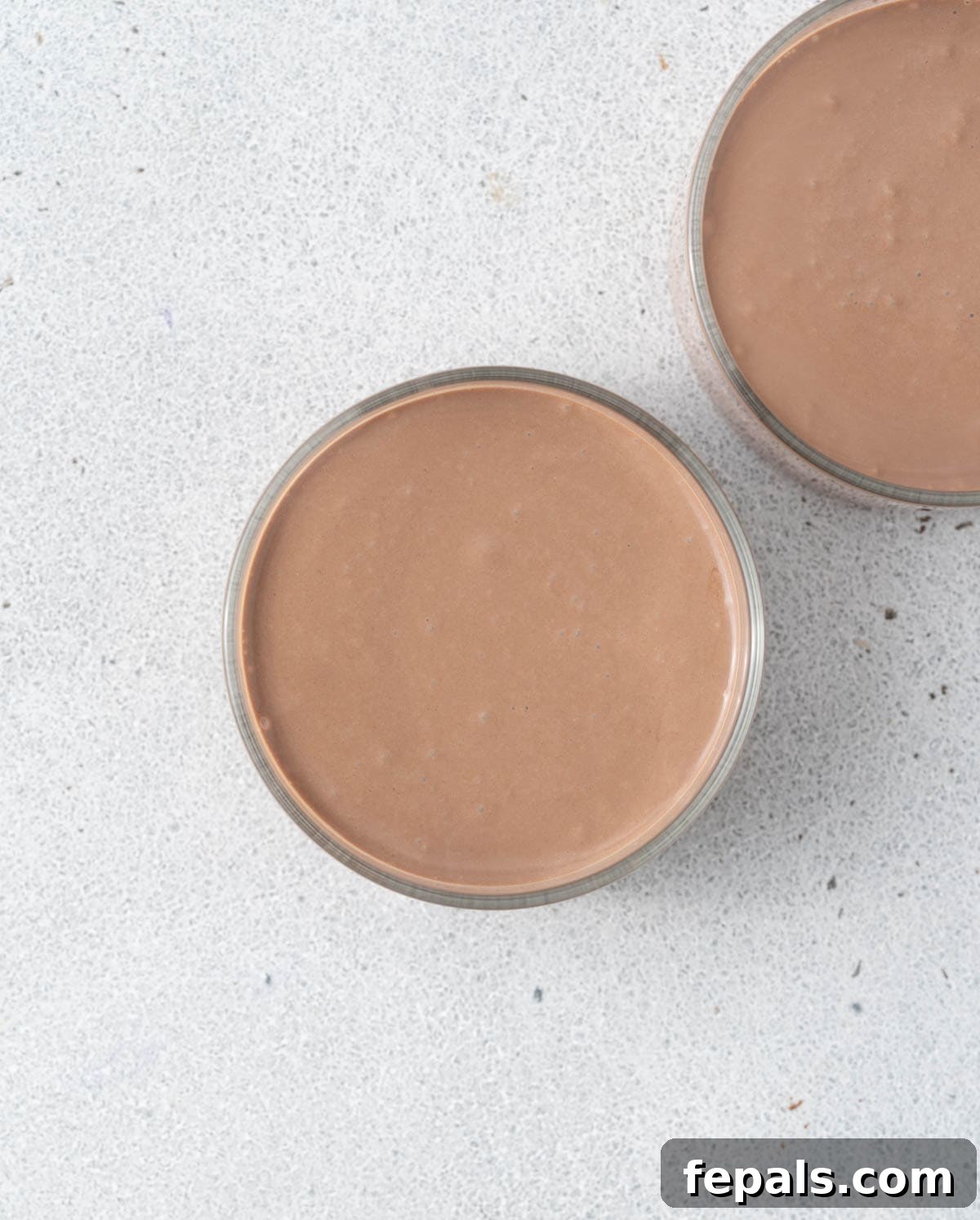 Two mousse-filled cups without toppings, smooth and creamy chocolate layer visible.