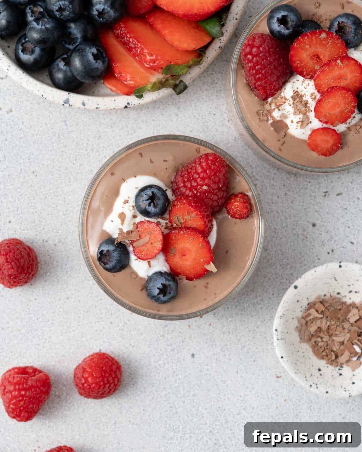 Overhead of mousse with fruit and whipped topping, framed by scattered berries.