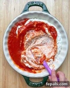 Crustless Pizza Cottage Bowl 13 cottage cheese and pizza sauce in a dish with a hand holding the spatula to mix it together.