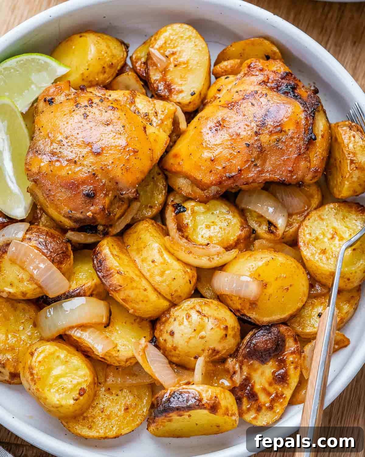 Zoomed-in look at perfectly roasted chicken thighs with caramelized edges and seasoned baby potatoes, glistening and ready to eat.