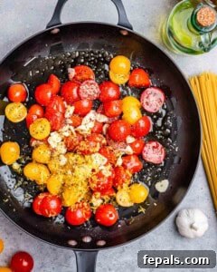 sliced tomatoes in a skillet with garlic and oil.