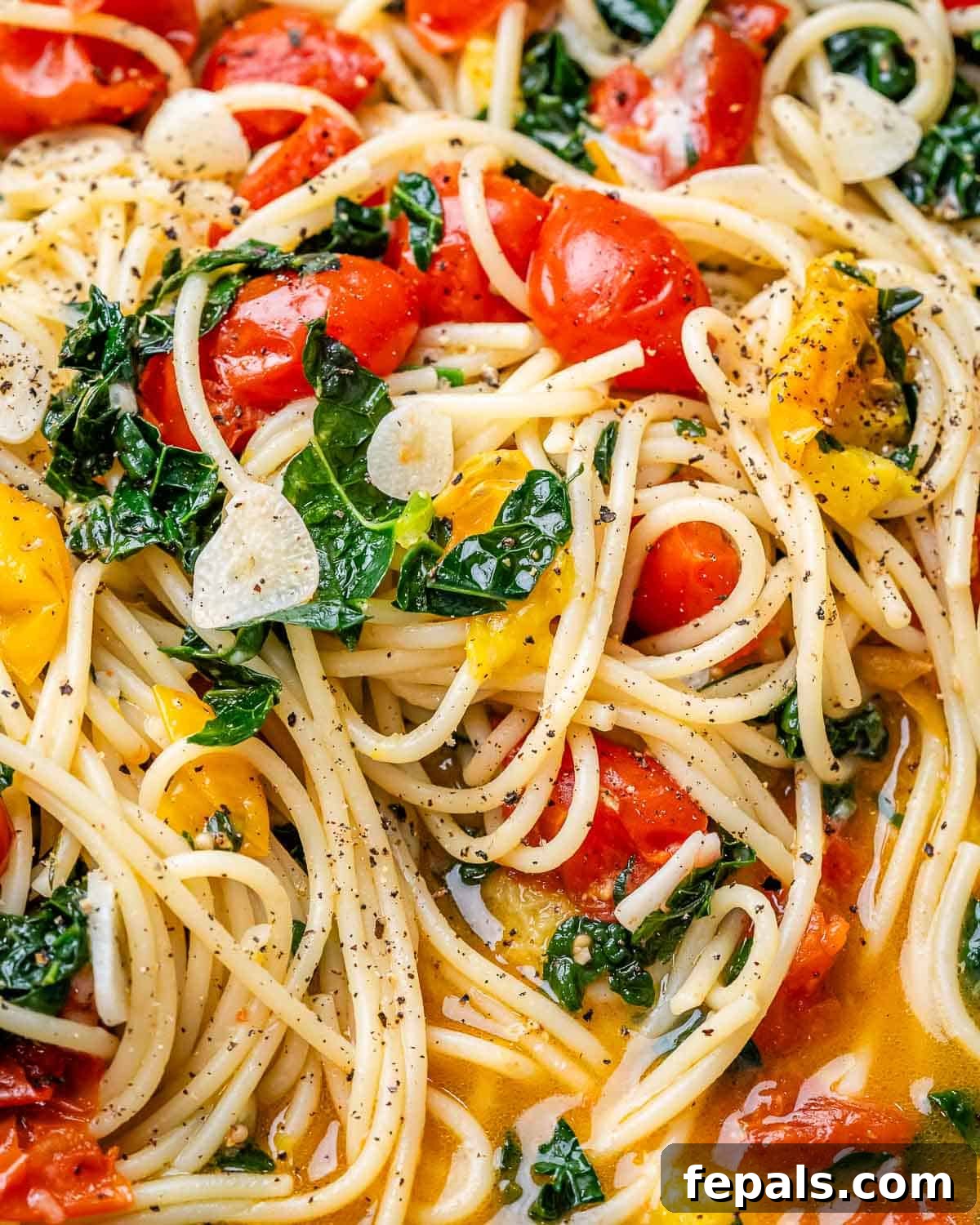 Pasta with tomatoes and kale in skillet. 
