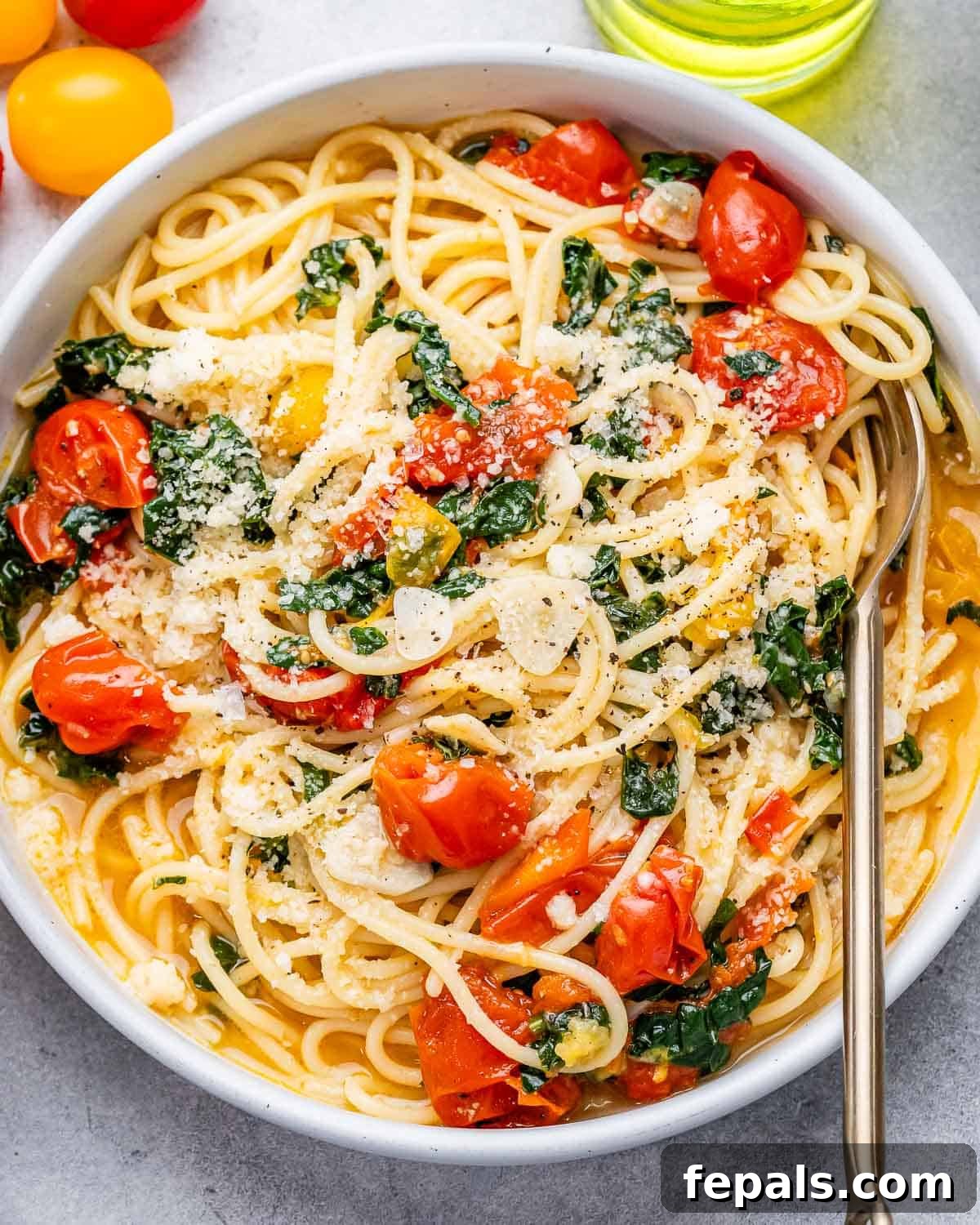 A bowl with tomato and kale spaghetti.