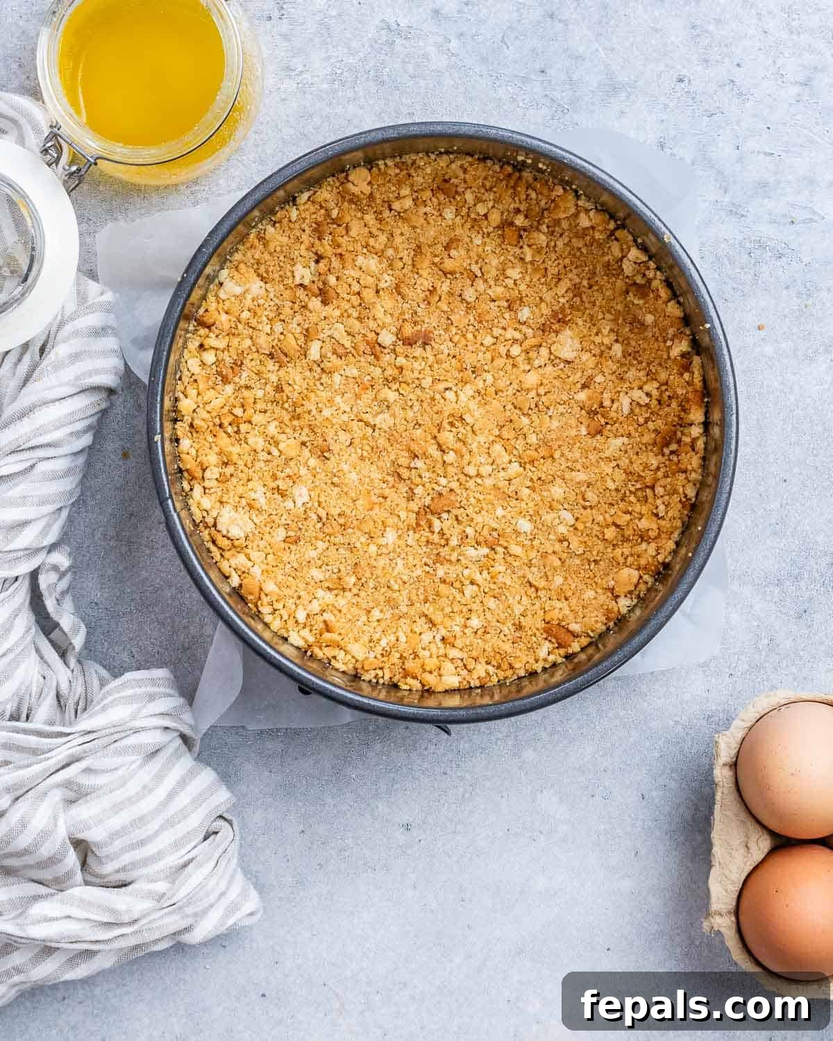 Graham cracker crust evenly pressed into the bottom of a springform pan, ready for baking.