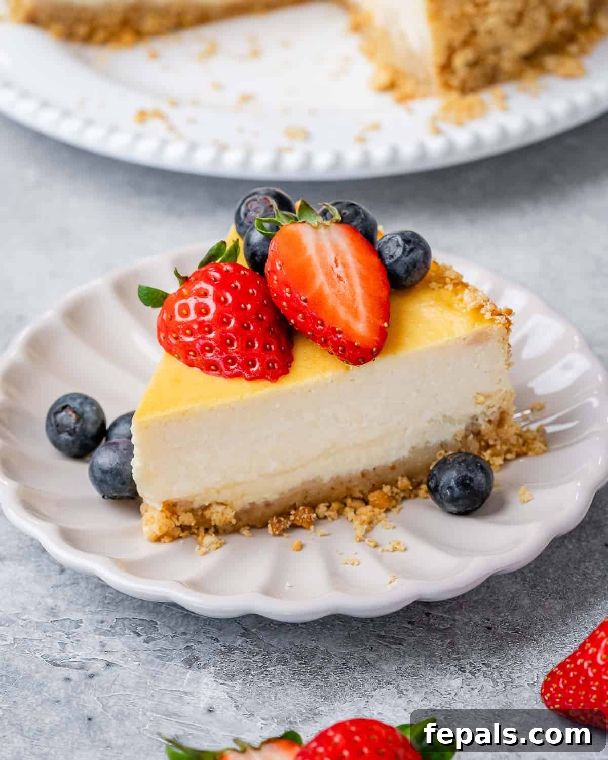 A single slice of cottage cheese cheesecake, perfectly set and creamy, served on a white plate with a generous garnish of mixed fresh berries.