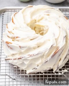 Tropical Coconut Bliss Cake 19 Frosted bundt cake cooling on a wire rack, topped with swirls of coconut cream cheese frosting.