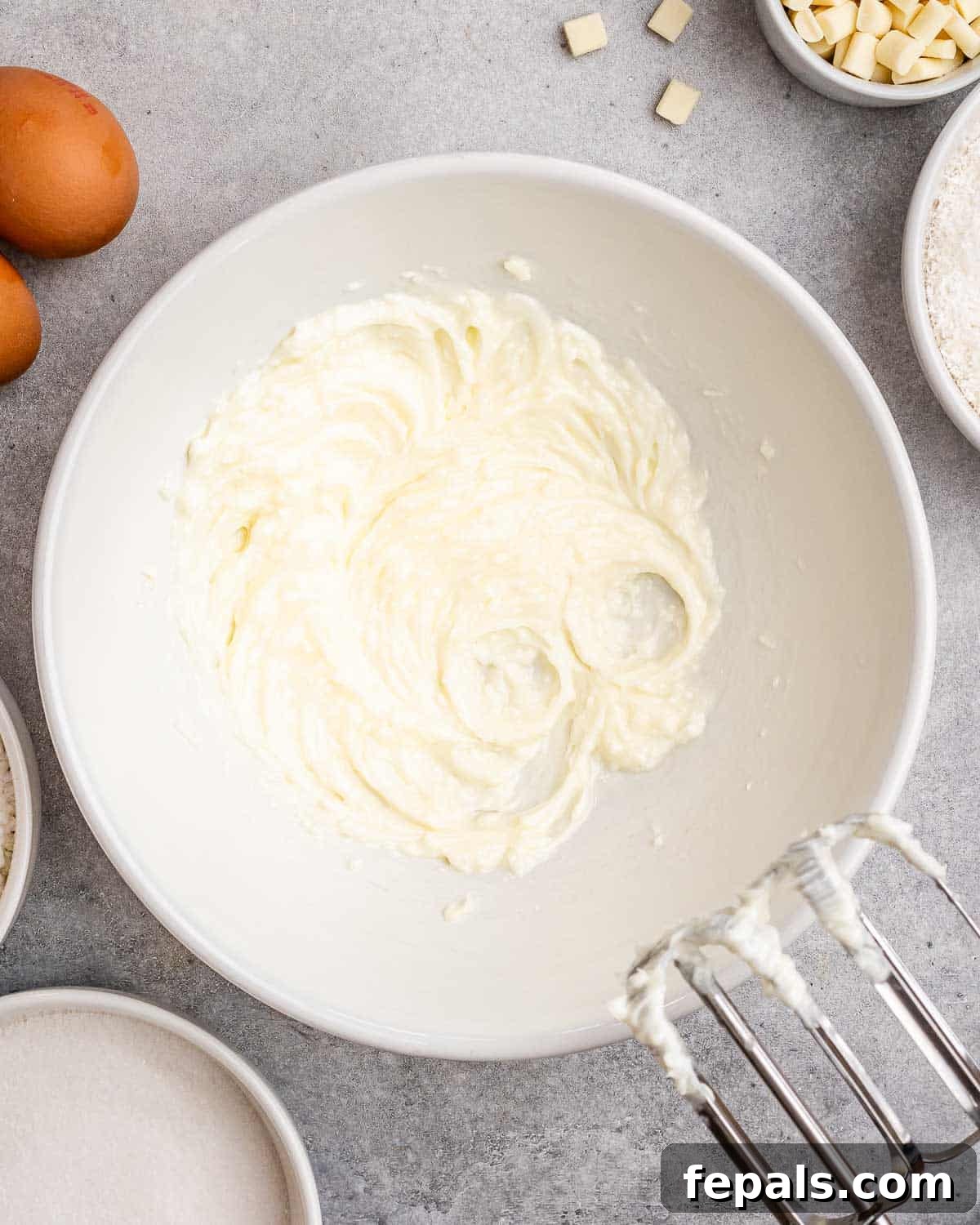 Tropical Coconut Bliss Cake 4 A light, fluffy base batter in a large mixing bowl, showing the creamy texture achieved after creaming together butter, coconut oil, and sugar with an electric mixer.