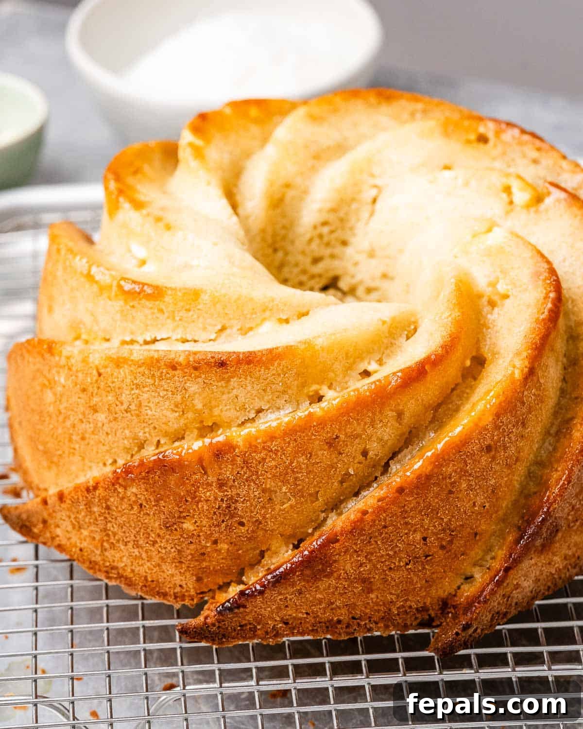 Tropical Coconut Bliss Cake 8 A freshly baked, golden-brown bundt cake rests on a wire rack, cooling gracefully after being removed from the oven, before any frosting or decoration has been applied.