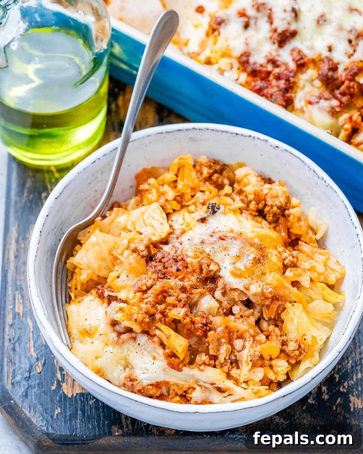 Easy Cabbage Roll Bake 7 A close-up shot of a single serving of Cabbage Roll Casserole in a white bowl, showing distinct layers of tender cabbage, rice, and a rich beef and tomato sauce, crowned with melted cheese.