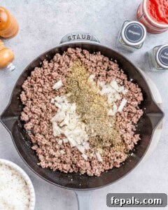 Easy Cabbage Roll Bake 10 Ground beef browning in a skillet with diced onions and minced garlic, seasoned with oregano and Italian seasoning.