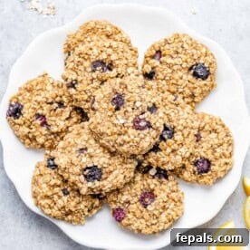 Soft-Baked Blueberry Oatmeal Cookies 13 Freshly baked oatmeal cookies on a round white plate, ready to be enjoyed.