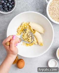 Soft-Baked Blueberry Oatmeal Cookies 14 The Banana is mashed with a masher in a bowl.
