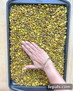 Hand spreading pistachios on a sheet pan.
