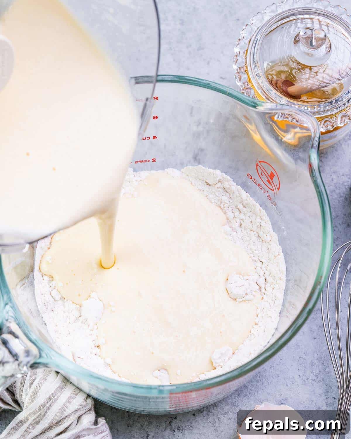The blended wet waffle mixture is poured into a large bowl containing all-purpose flour and baking powder.