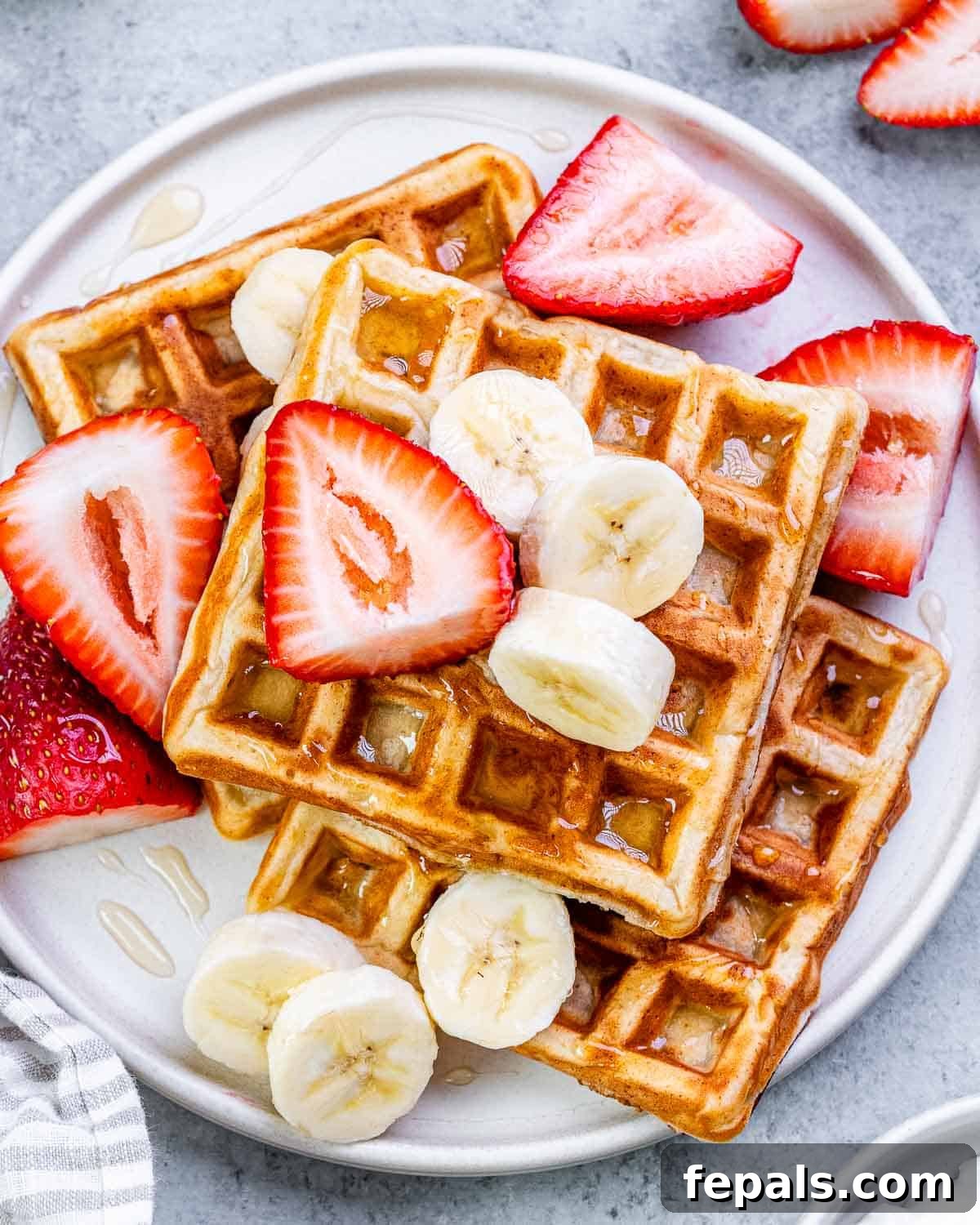A close-up shot of a single, perfectly golden cottage cheese waffle on a pristine white round plate, showcasing its fluffy texture and inviting aroma.