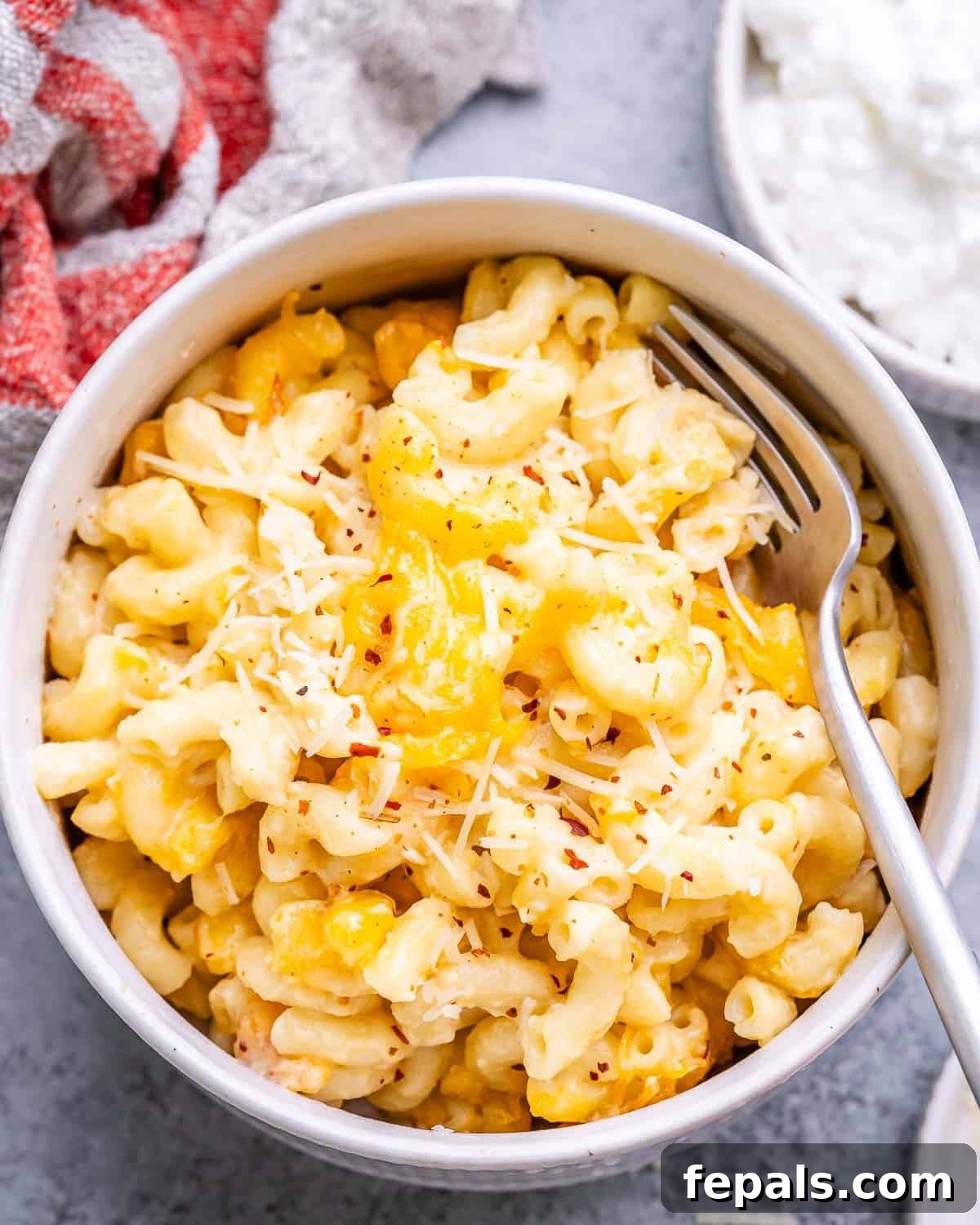 Velvet Cottage Mac and Cheese 8 A serving of cottage cheese mac and cheese in a bowl, garnished with black pepper and chili flakes, with a fork.