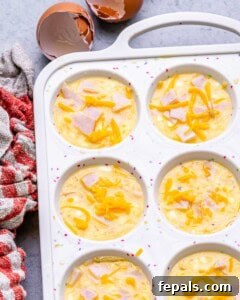 Process shot showing the egg mixture, topped with chopped turkey, being poured into a silicone muffin tin.