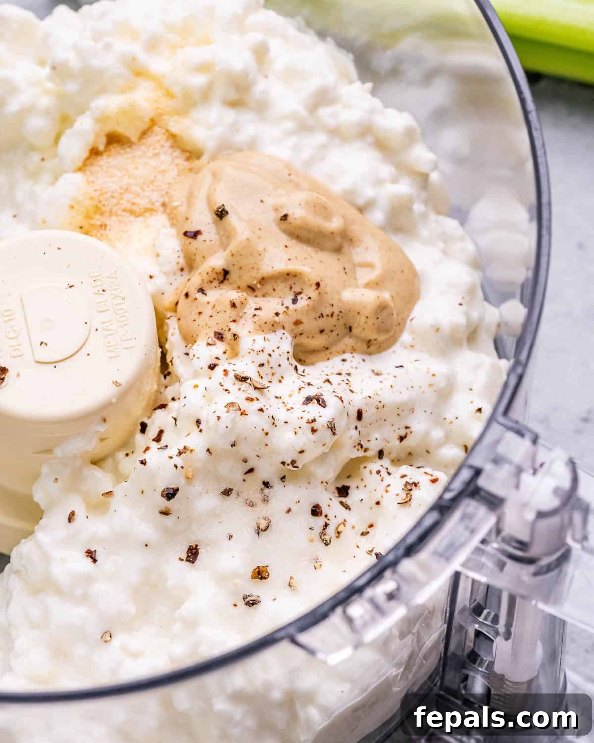 Light and Creamy Cottage Chicken Salad 4 A food processor bowl containing creamy cottage cheese, Dijon mustard, lemon juice, onion powder, salt, and pepper, ready to be blended into a smooth dressing.
