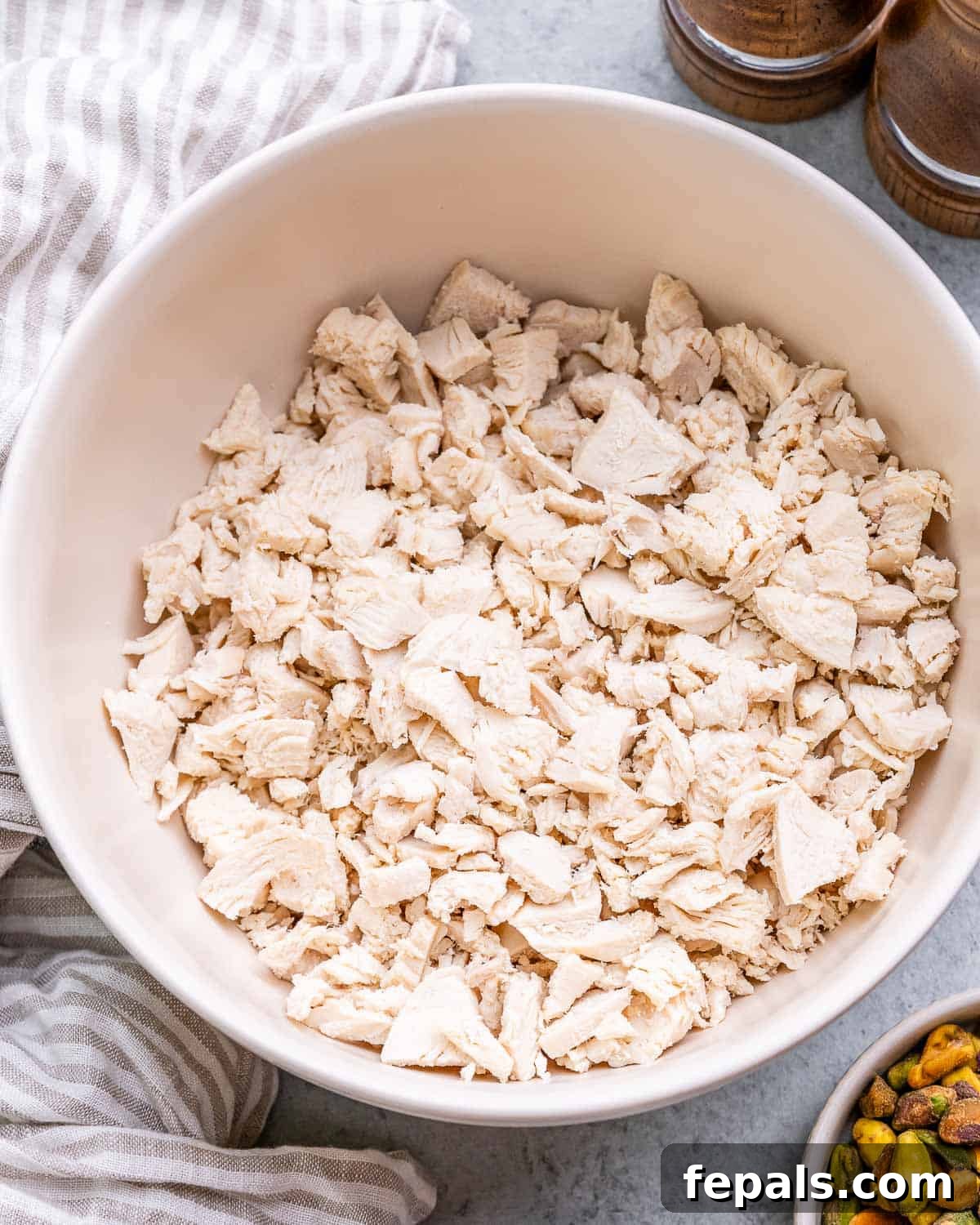 Light and Creamy Cottage Chicken Salad 5 Finely shredded or chopped rotisserie chicken piled in a large white mixing bowl, ready for other ingredients.
