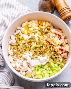 Chopped ingredients on top of chicken in a white bowl.