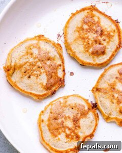 Banana cottage cheese pancakes cooking in a non-stick pan.