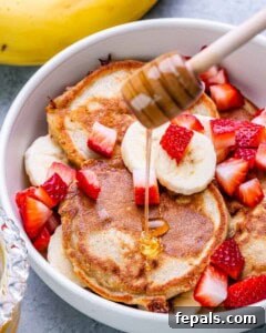 Drizzling honey on cottage cheese pancakes with sliced banana and strawberry