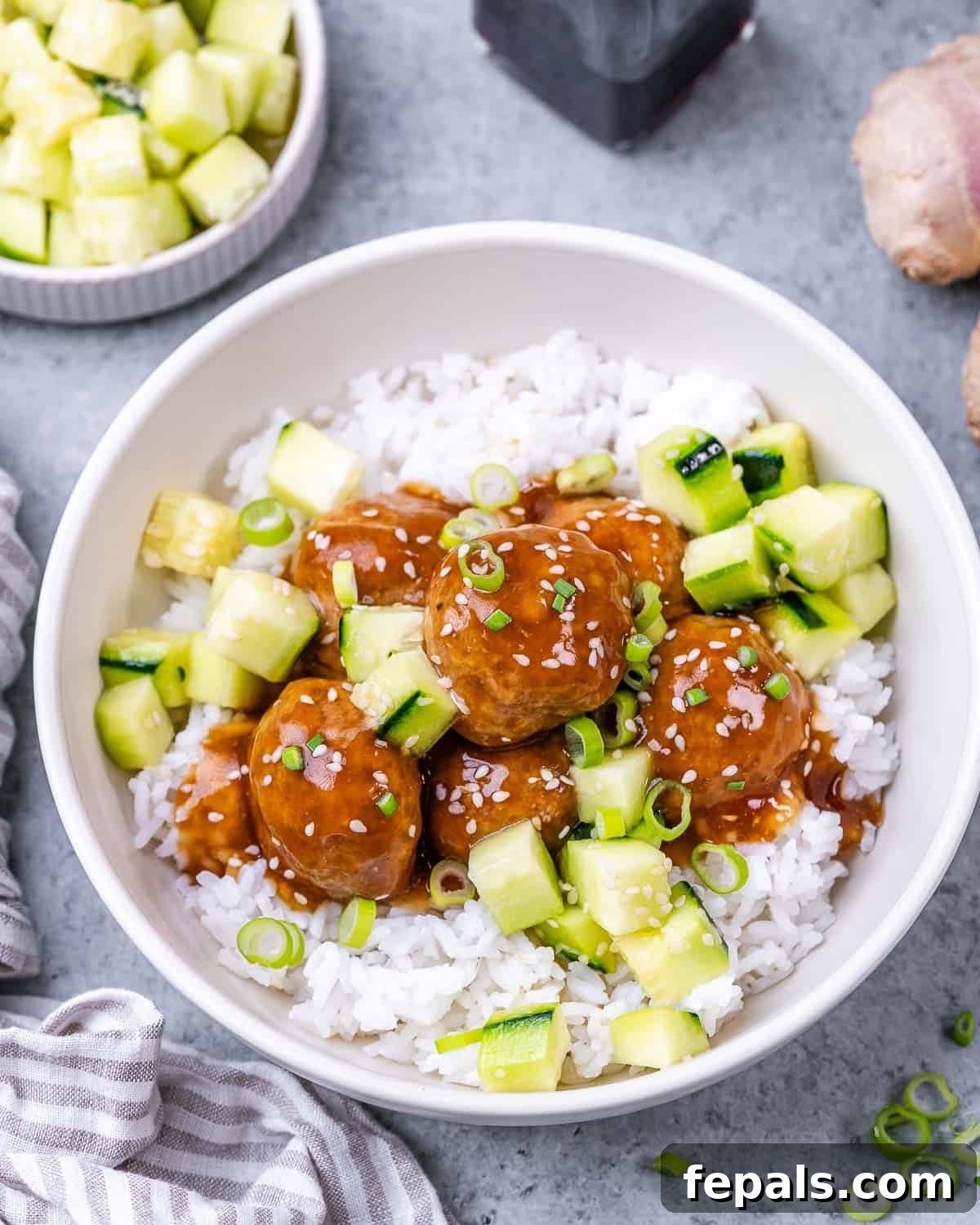 Sticky Teriyaki Turkey Meatballs 13 Teriyaki turkey meatballs served over a bed of rice, garnished with fresh cucumber slices and green onions.