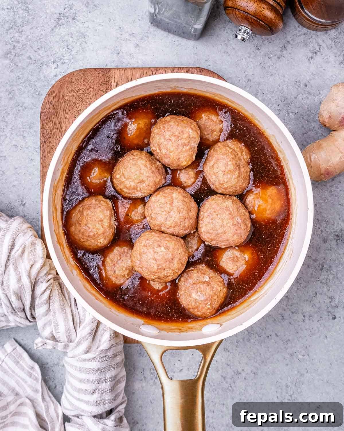 Sticky Teriyaki Turkey Meatballs 7 Baked meatballs coated in rich teriyaki sauce in a saucepan, ready to serve.