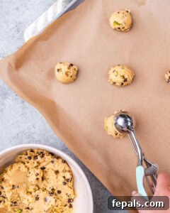 Cookie dough balls scooped and spaced out on a parchment-lined baking sheet, ready to be baked.