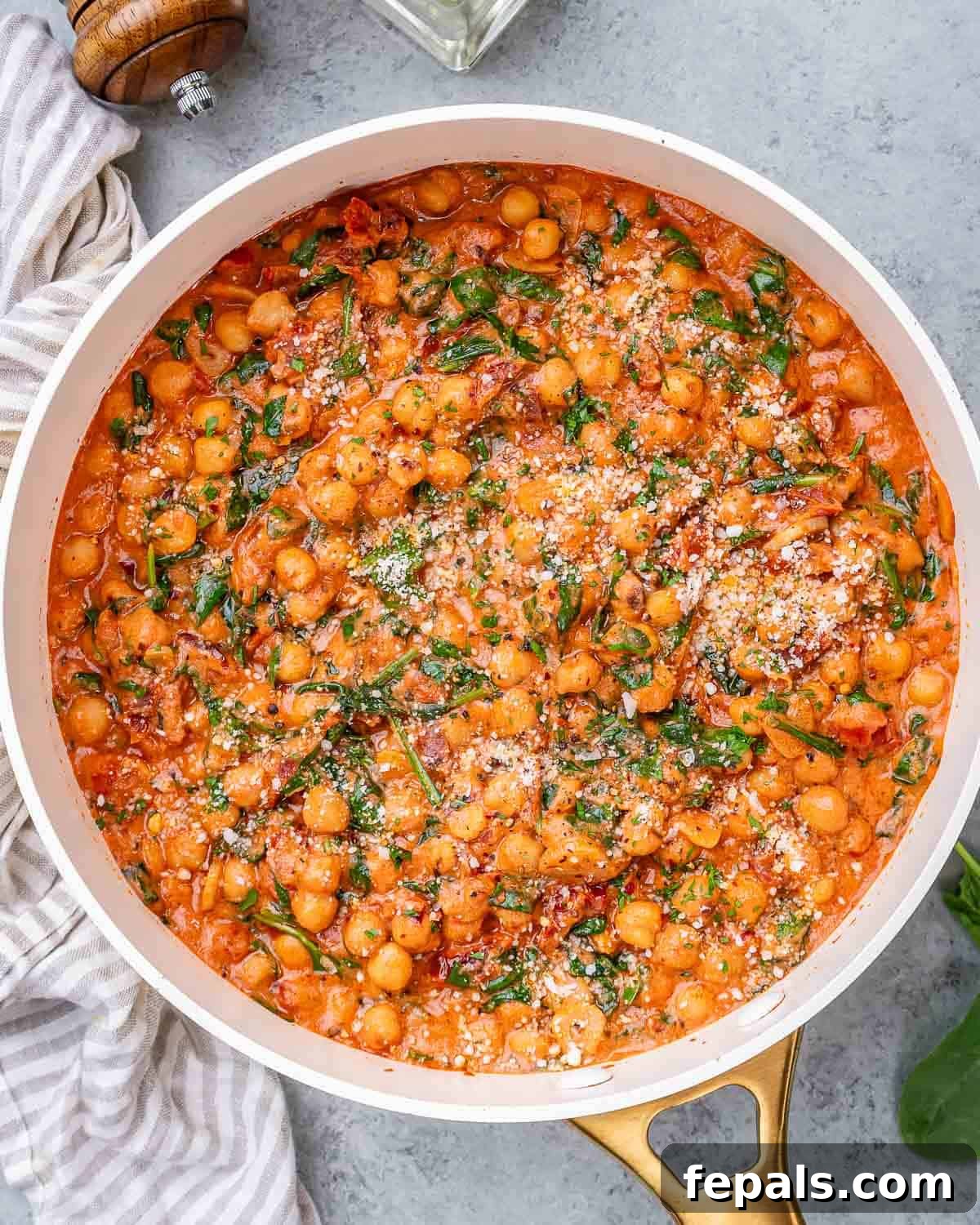 Overhead shot of creamy Marry Me Chickpeas simmering in a rich, orange-hued tomato and coconut cream sauce, garnished with fresh basil.