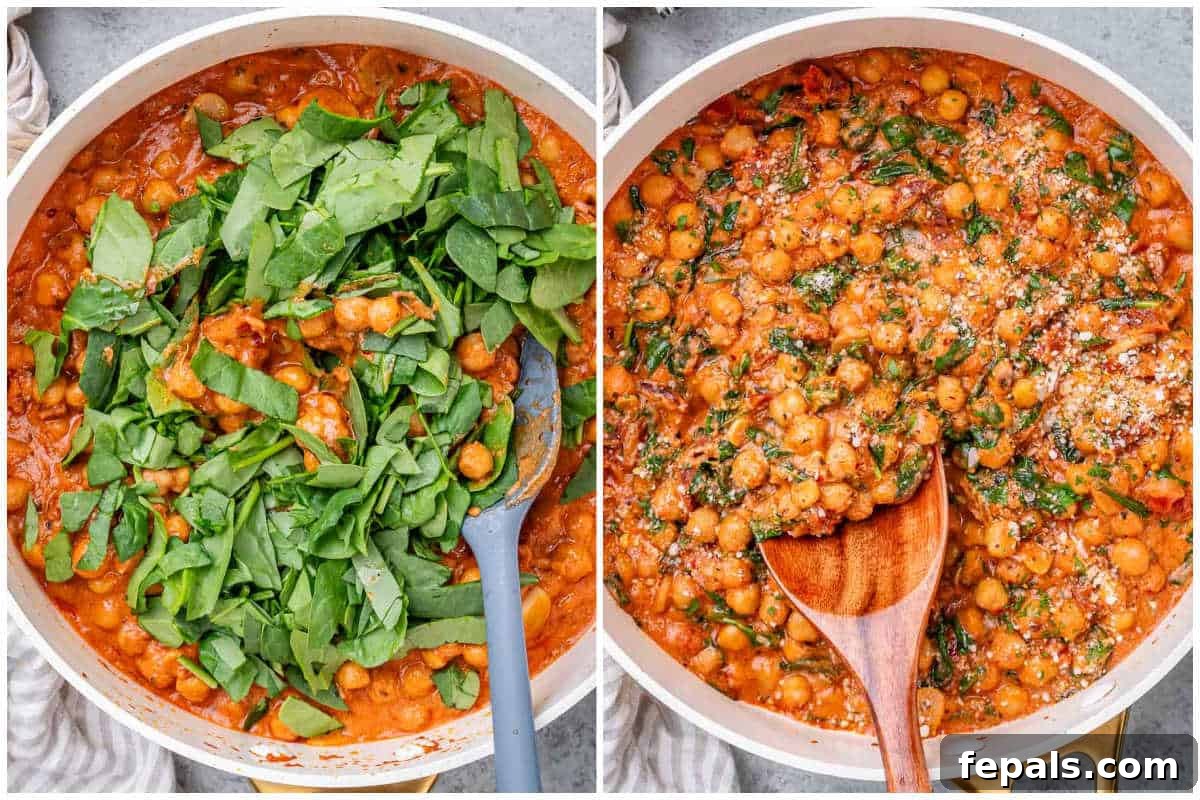 Process shot of fresh baby spinach being added on top of the creamy chickpea and tomato sauce mixture in a pan, ready to be wilted.