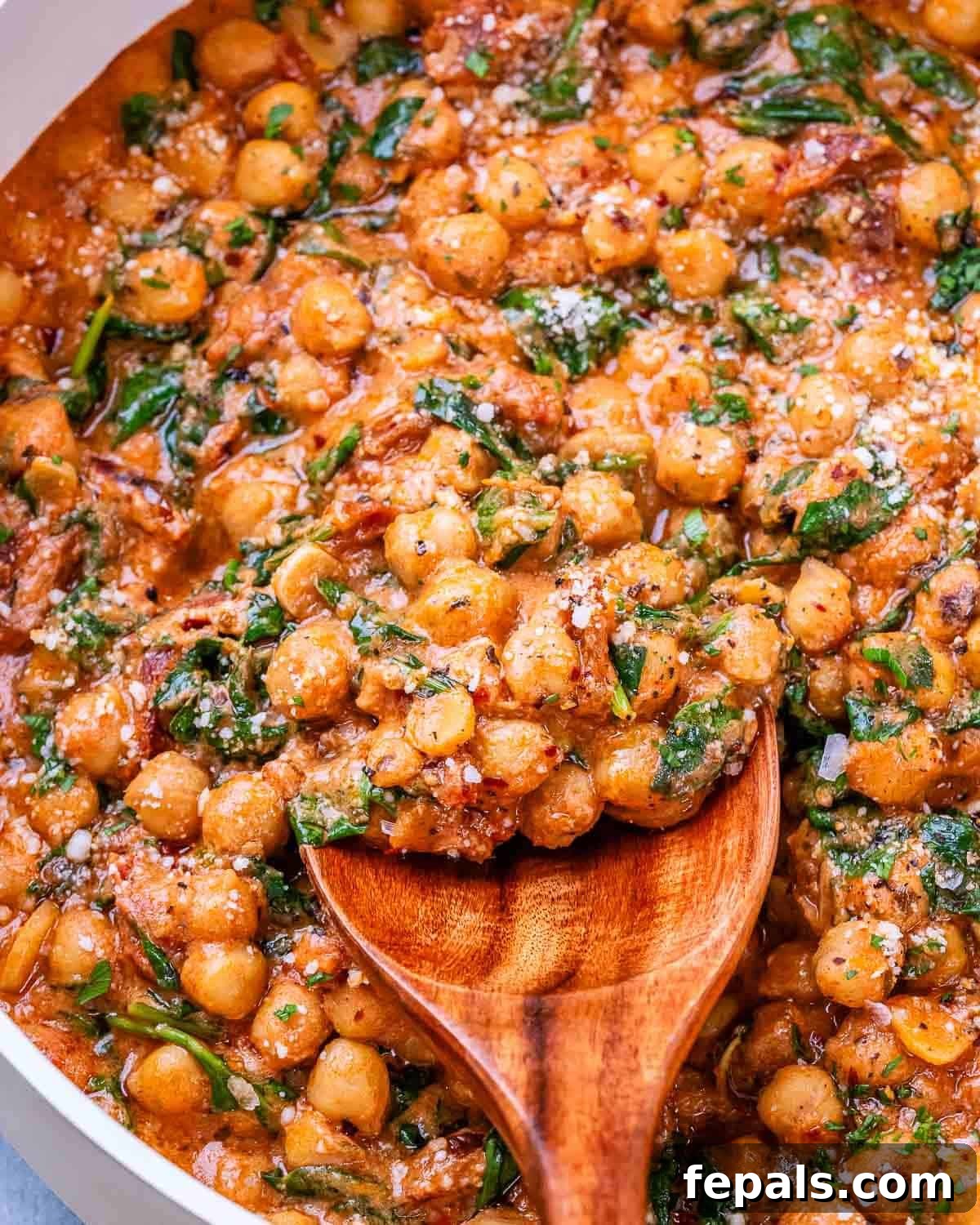 Close-up of a creamy serving of Marry Me Chickpeas, showcasing the rich texture, vibrant green spinach, and melted Parmesan cheese, ready to be enjoyed.