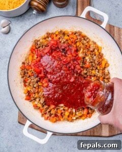 Comforting Ground Turkey Pasta 10 Fire-roasted tomatoes and salsa being poured into the skillet on top of the turkey and veggies.