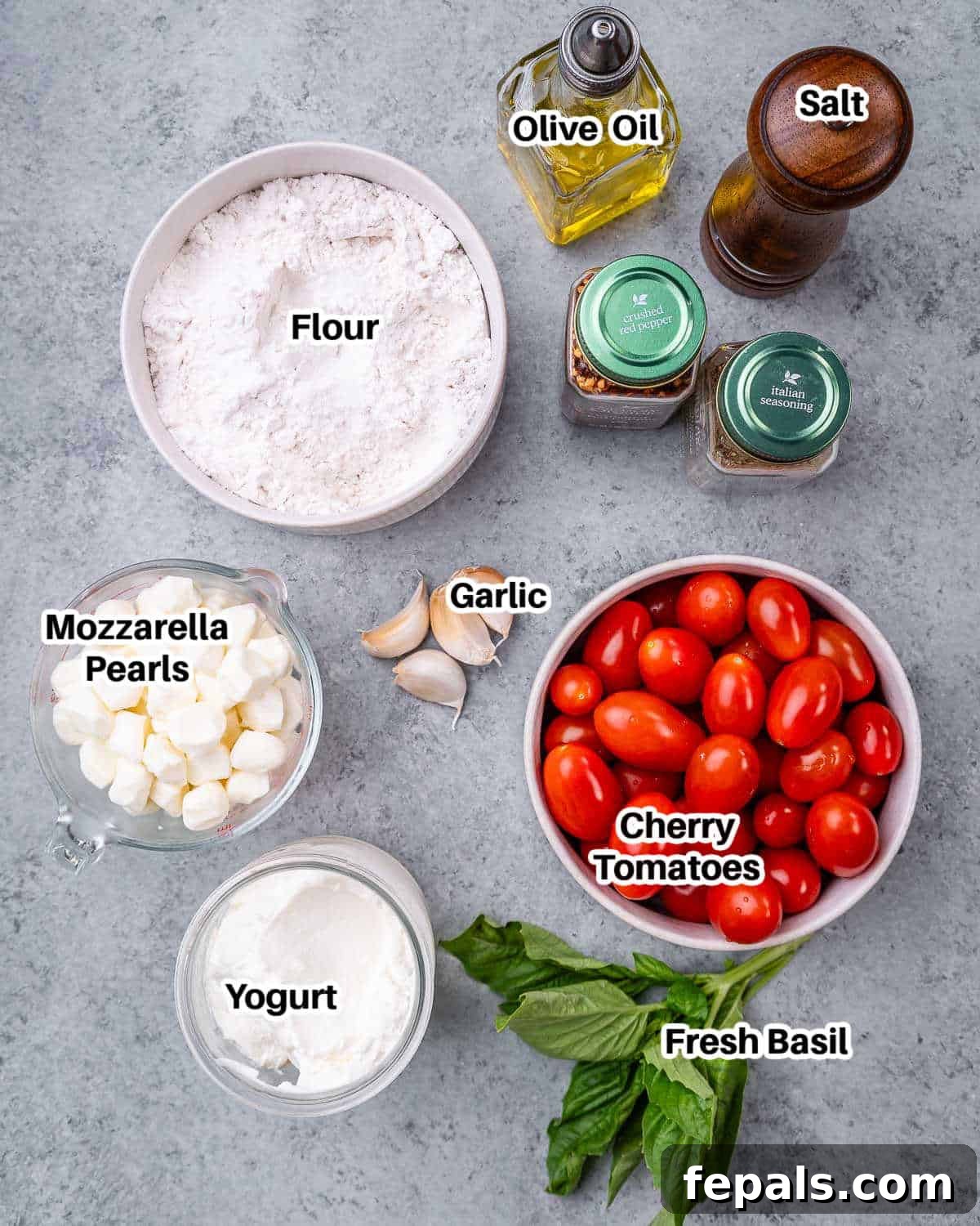 Garden-Fresh Bruschetta Pizza 3 A flat lay photograph showcasing all the fresh ingredients needed to make bruschetta pizza, including self-raising flour, Greek yogurt, fresh garlic, cherry tomatoes, mozzarella pearls, olive oil, and a bunch of basil.
