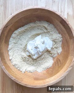 Low-Carb Almond Bagels 16 Greek yogurt added over the almond flour mixture in a wooden bowl.