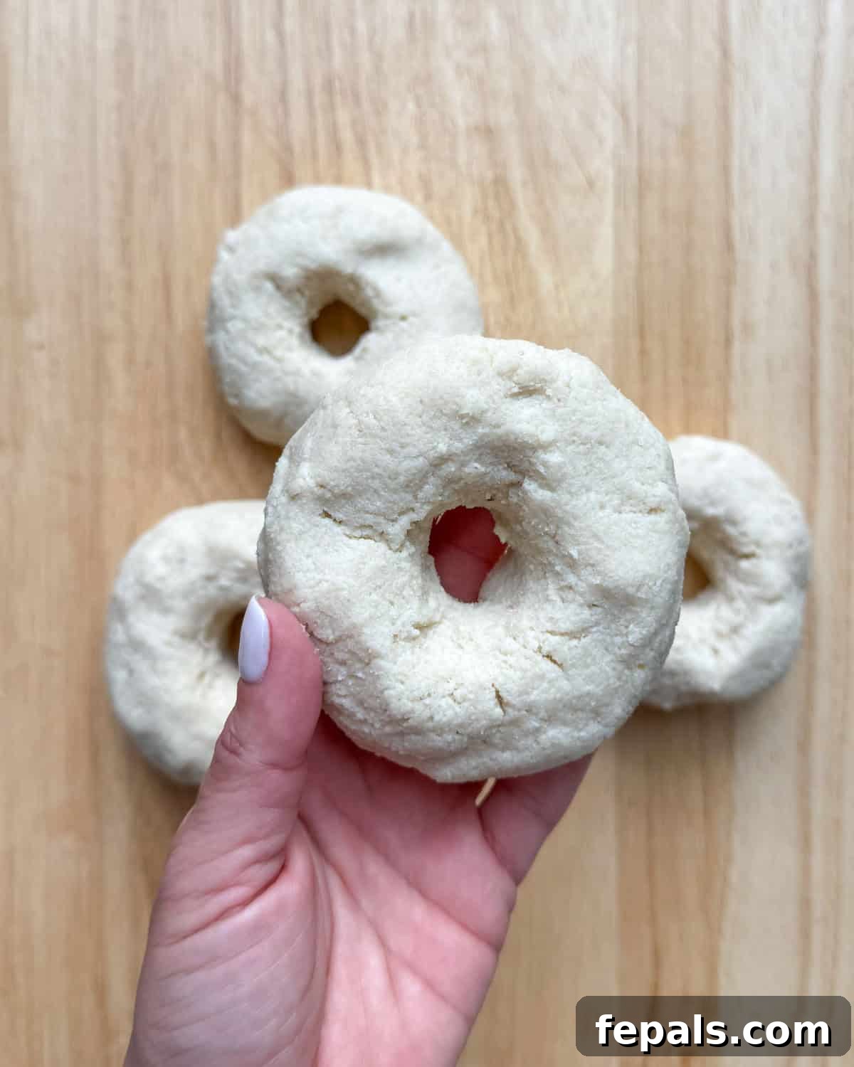 Low-Carb Almond Bagels 9 Dough sections carefully formed into traditional bagel shapes with a hole in the center.