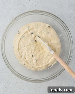 Top view of glass bowl with muffin batter being mixed with chocolate chips in it.