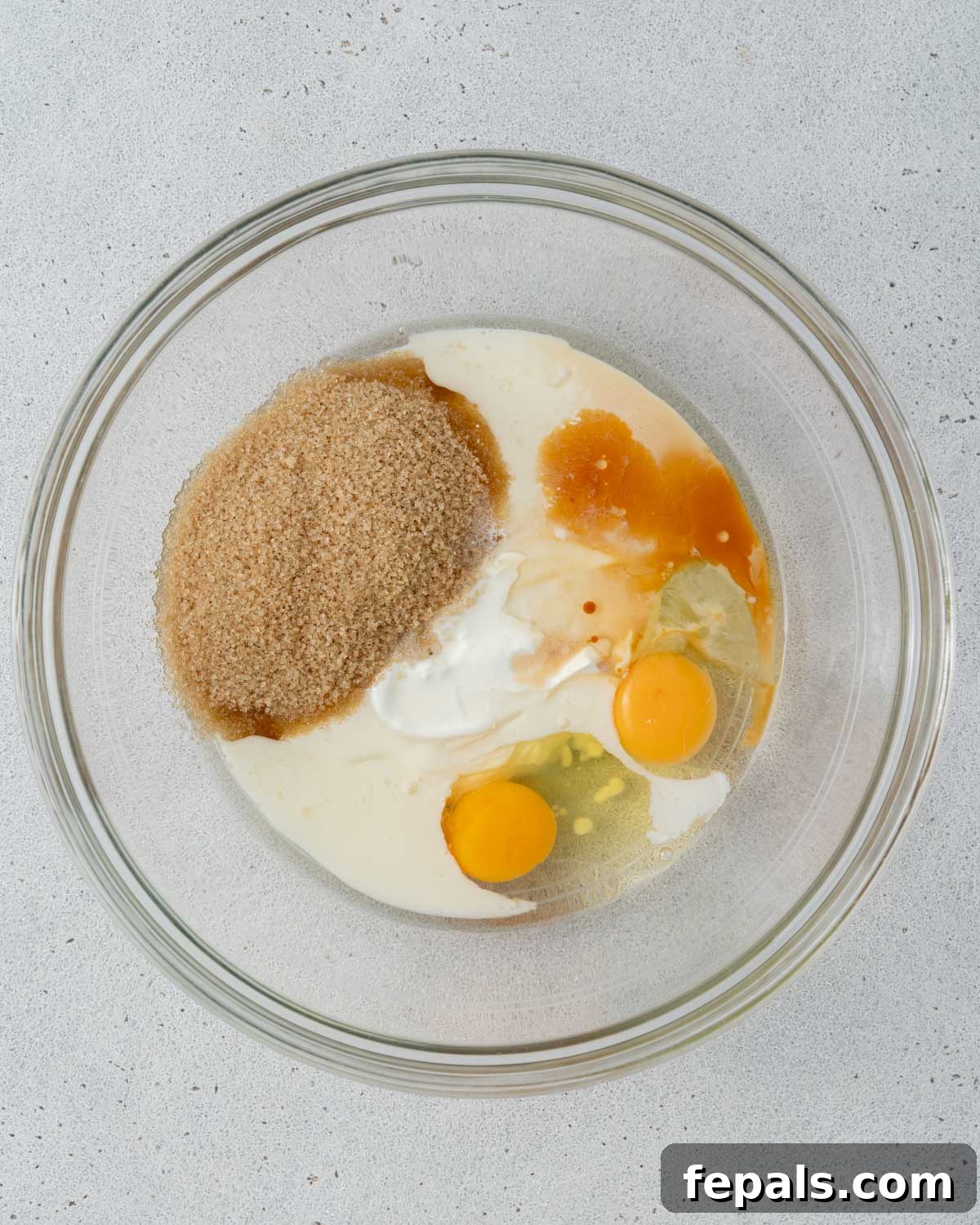 Wet ingredients and sugar added to a mixing bowl, ready to be whisked.