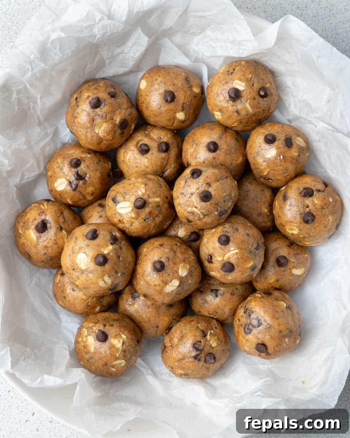 A bowl filled with freshly made peanut butter protein balls, neatly arranged on parchment paper.