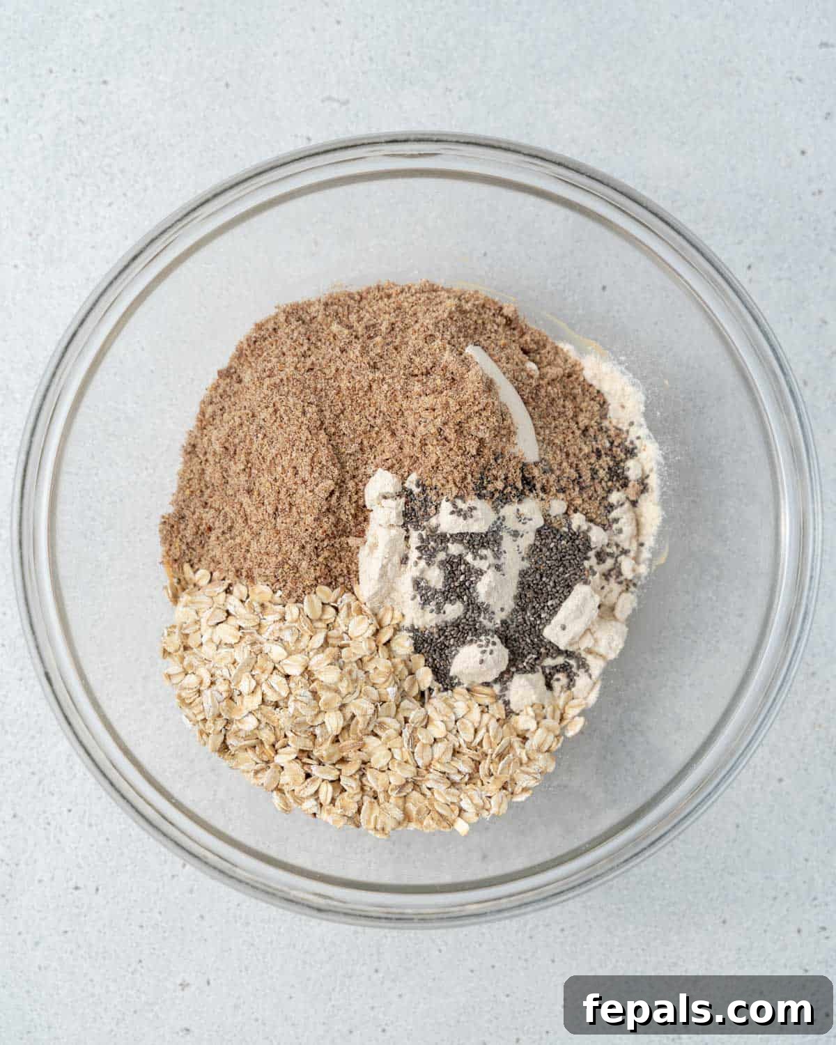 Flaxseed meal, oatmeal, and protein powder added over the peanut butter mixture in a bowl.