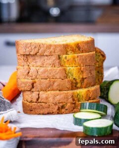 Moist Zucchini Carrot Loaf 13 Stack of five thick slices of zucchini carrot bread with fresh produce in the background.