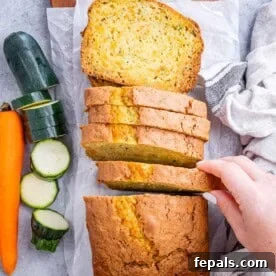 Hand grabbing a slice of zucchini and carrot bread.