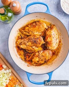 Seasoned chicken breasts browning in a skillet before being added to the rice mixture.