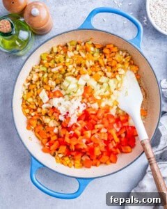 Sautéed carrots, celery, onions, and bell peppers cooking in a skillet.