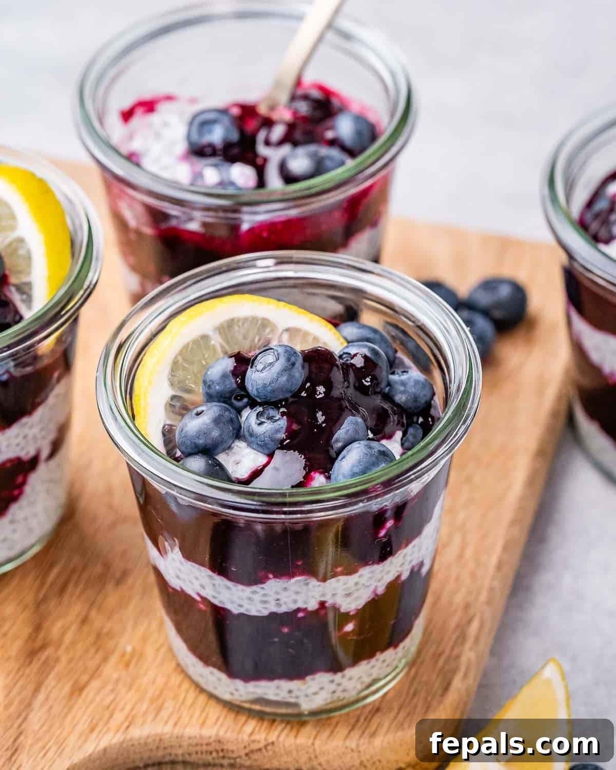 Close-up of a blueberry lemon chia pudding jar on a wooden board, showing the vibrant layers of creamy lemon chia pudding and rich blueberry compote.